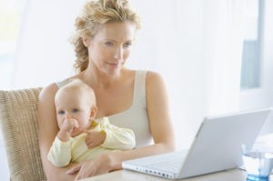 Woman holding a baby in front of a laptop