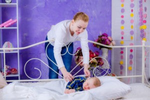 woman putting a toddler to bed