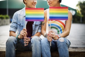 Two women holding LGBTQ flags
