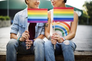 Two women holding LGBTQ flags