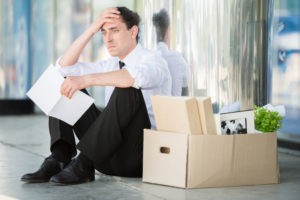 Upset man sitting with a box of belongings after being fired